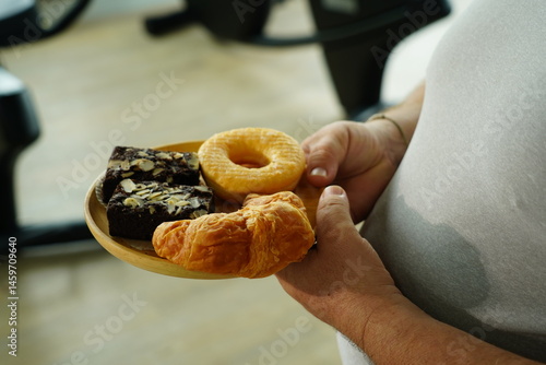 Obraz na płótnie Fat man holding a tray of breakfast bread, brownies, donuts, croissants with flour and sugar. w salonie