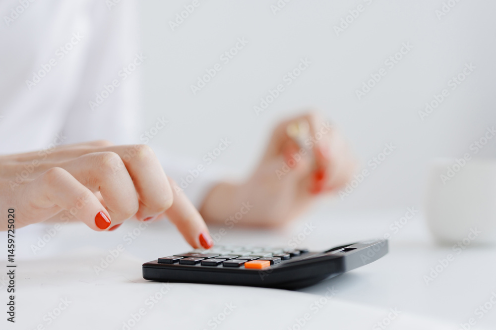 Fototapeta premium Calculating expenses with a calculator in a bright workspace during the daytime hours