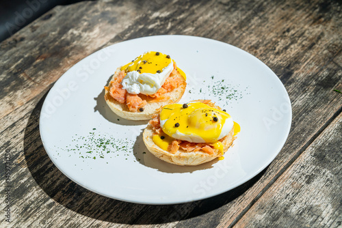 Egg benedict or poached egg with salmon on white plate. Isolated by wooden background or table. Food photography