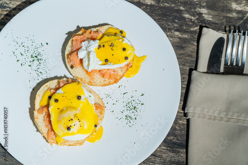 Egg benedict or poached egg with salmon on white plate. Isolated by wooden background or table. Food photography