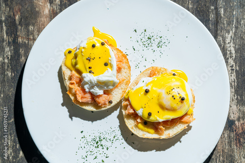 Egg benedict or poached egg with salmon on white plate. Isolated by wooden background or table. Food photography