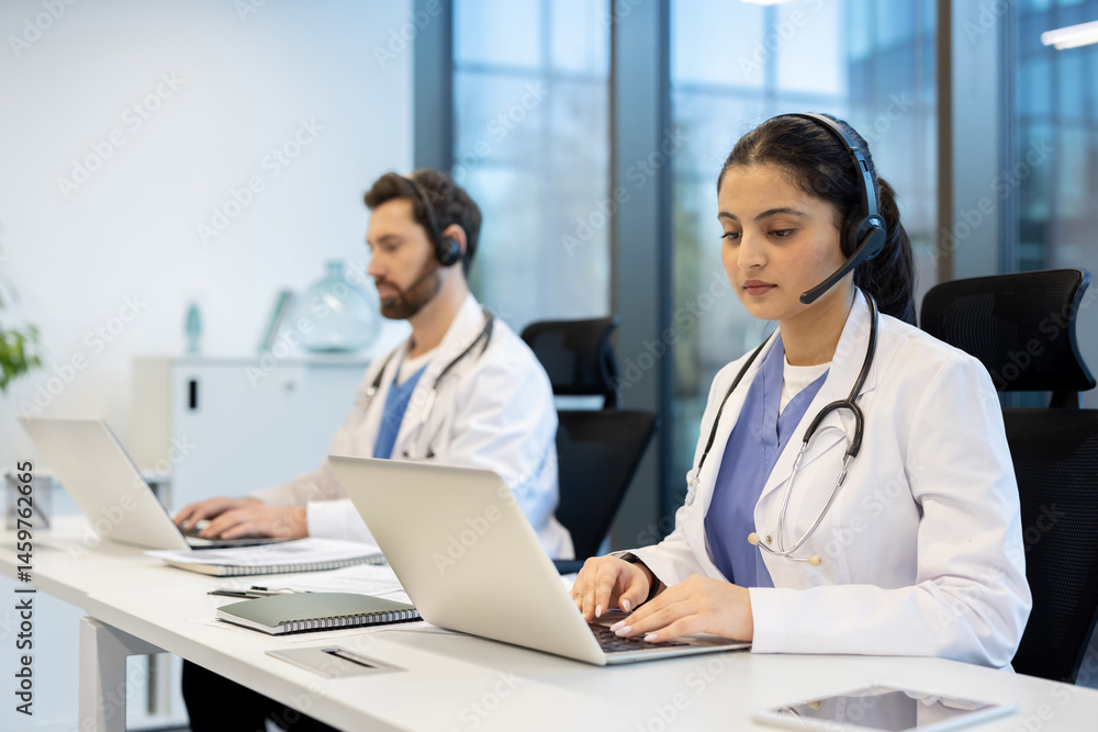 Two doctors are seen in an office setting, wearing headsets and using laptops. They may be providing remote medical consultations.