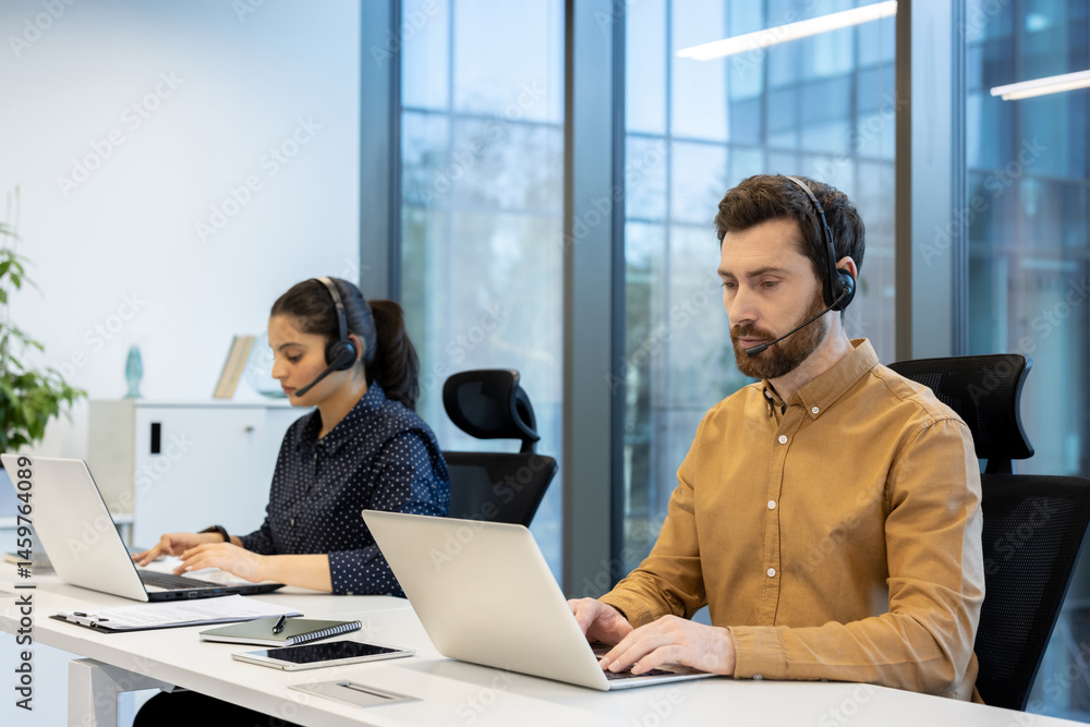 Two customer service representatives working in a modern office environment, each using laptops and headsets.