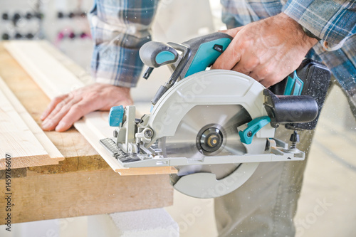 Obraz na płótnie A skilled craftsman operates a circular saw on a wooden plank, showcasing precision and craftsmanship in a well-lit workshop environment, highlighting woodworking techniques w salonie