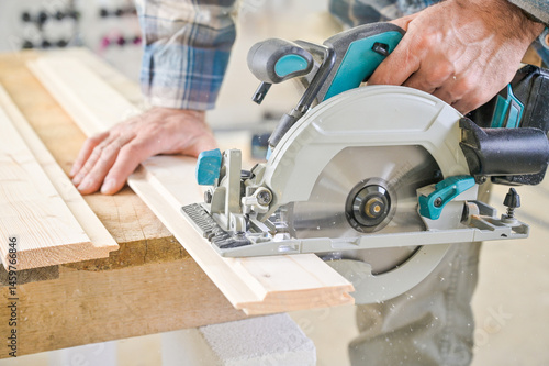 A skilled craftsman operates a circular saw on a wooden plank, showcasing precision and craftsmanship in a well-lit workshop environment, highlighting woodworking techniques