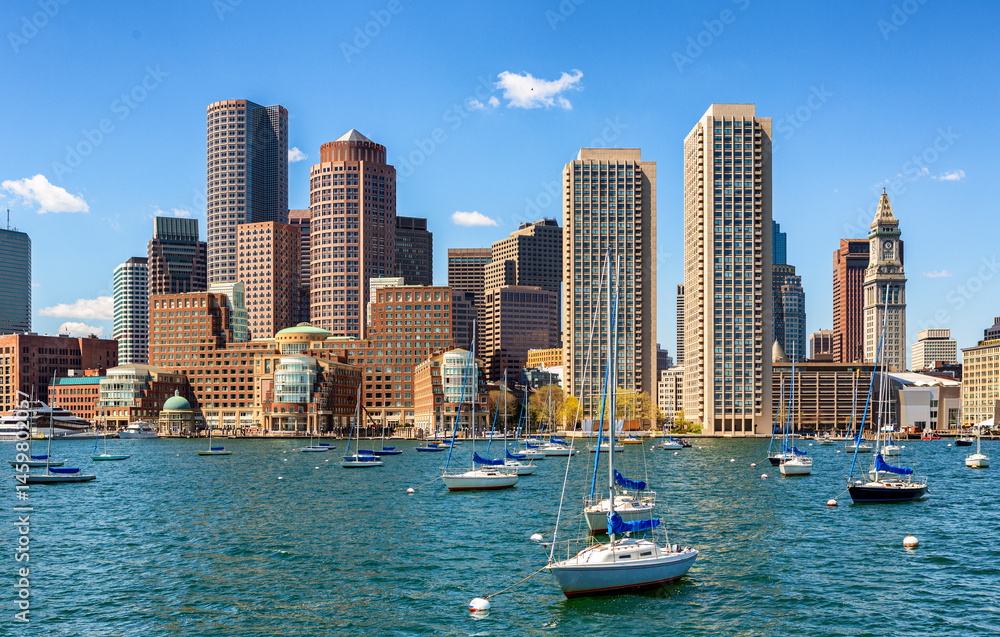 Obraz premium A vibrant daytime view of Boston’s downtown skyline featuring marina with boats, modern skyscrapers, and historic architecture