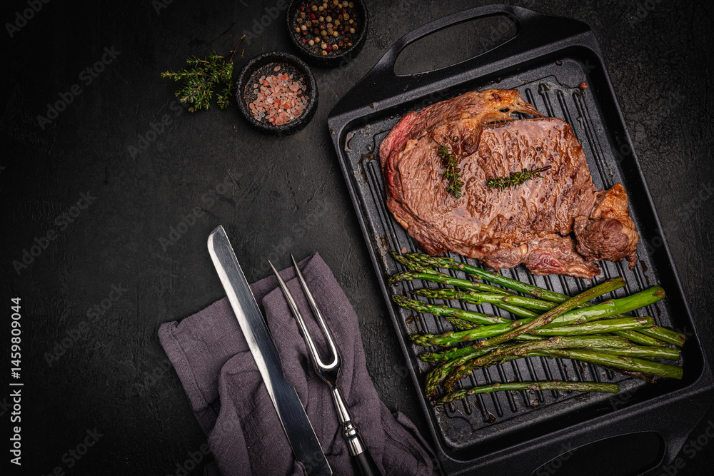 Beef grill steak with green asparagus on a grill pan. Healthy dinner or lunch, top view. High quality photo