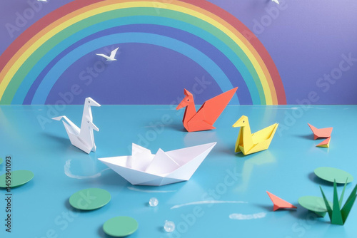 Vibrant Origami Creatures on Serene Pond Under Rainbow Sky with Flying Birds