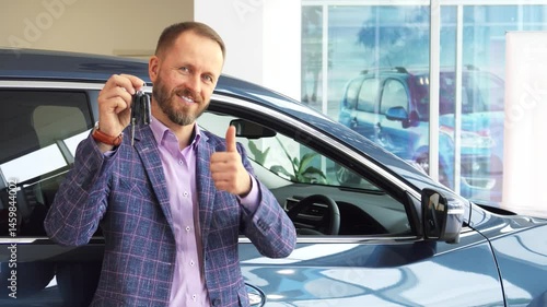 Confident car seller showcases quality vehicle with keys and a thumbs up