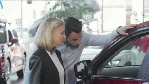 Joyful couple exploring their dream car at the dealership