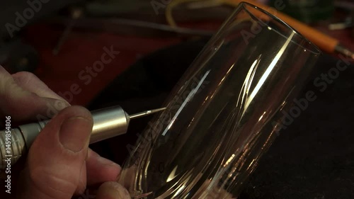 Caucasian engraver meticulously crafting intricate designs on glass