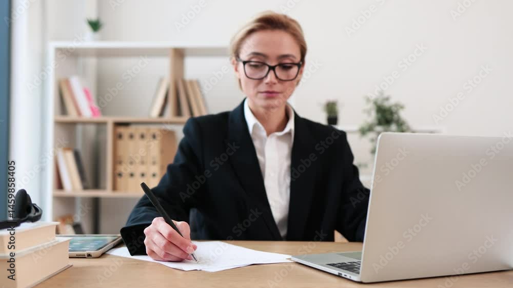 Mature woman, professional appearance, working with laptop at office desk. Wearing eyeglasses, formal attire, indoors. Concept of business, technology, concentration, problem solving Mature woman, professional appearance, working with laptop at office desk. Wearing eyeglasses, formal attire, indoors. Concept of business, technology, concentration, problem solving
