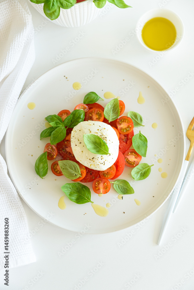 Salad Caprese with tomato, cherry, mozzarella and basil leaves on white wooden table Salad Caprese with tomato, cherry, mozzarella and basil leaves on white wooden table