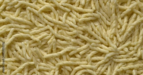 Cooked trofie pasta background texture. In Ligurian cuisine, trofie is most typically served with a pesto sauce. Table spin. 