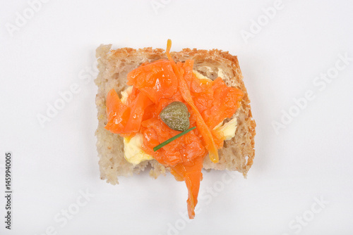 Obraz na płótnie A piece of bread topped with vegan carrot lox, cream cheese, and a caper is centered on a white background w salonie