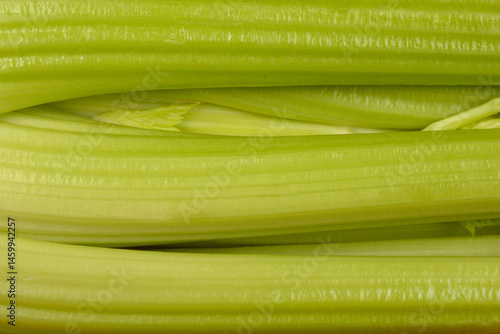 A very close-up shot focuses on the ribbed texture and vibrant green color of fresh celery stalks