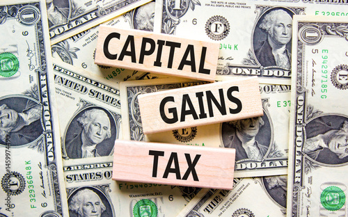 Capital gains tax symbol. Concept words Capital gains tax on beautiful wooden blocks. Dollar bills. Beautiful background from dollar bills. Business and capital gains tax concept. Copy space.