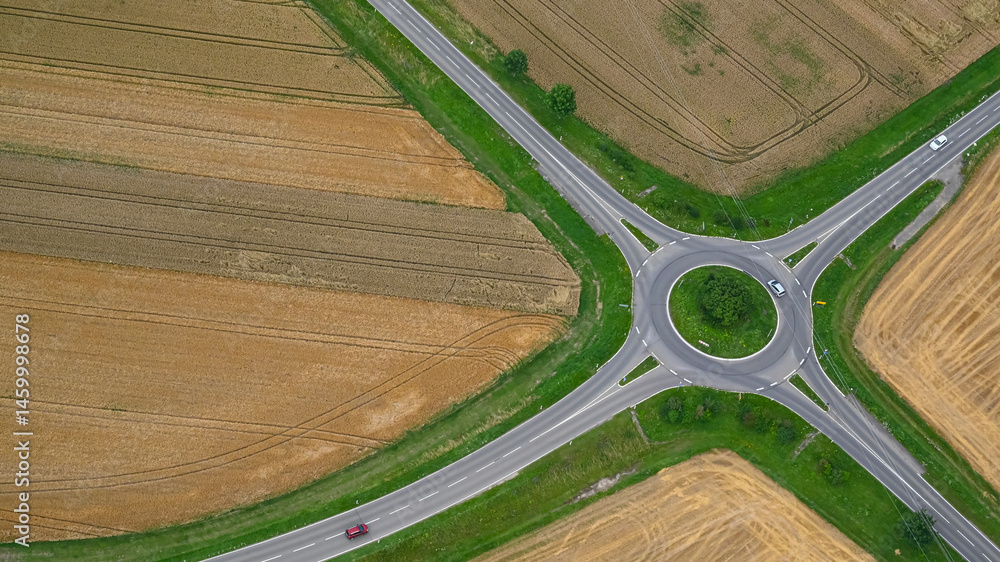 Obraz premium Country road, highway and traffic circle from above with drone or from an airplane with vehicles; trucks and cars on the road.