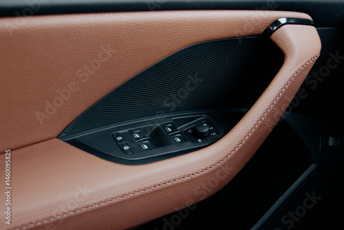 Car interior detail: brown leather door panel with controls Interior design and functionality in an automotive setting