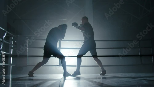 Boxers sparring in dark gym with blue backlight