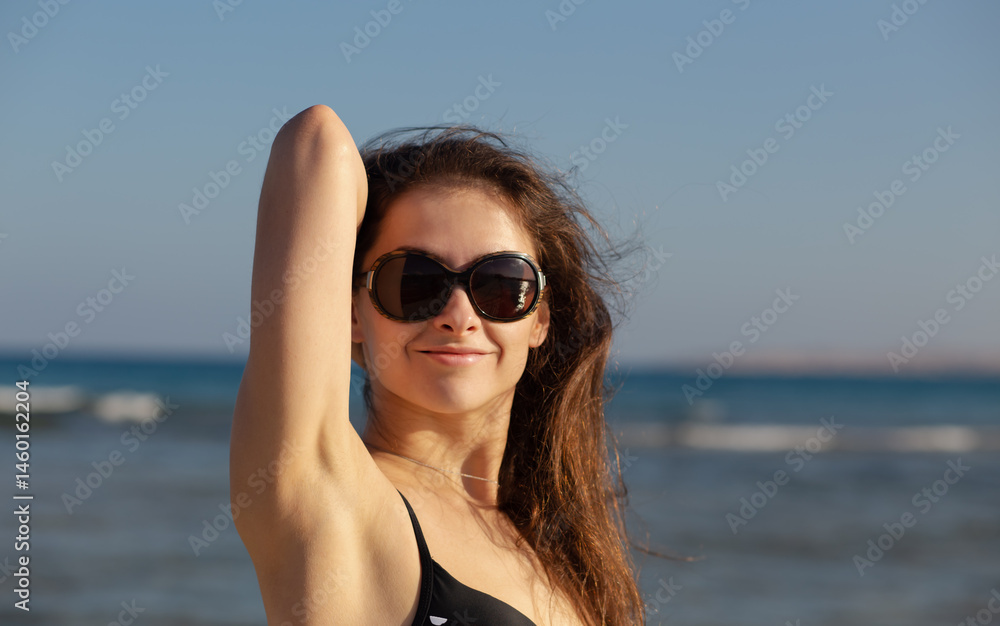 Beautiful happy enjoying woman in fashion style eyeglasses and long brown hair posing and looking on the blue sea and sky background. Closeup outdoor nature Beautiful happy enjoying woman in fashion style eyeglasses and long brown hair posing and looking on the blue sea and sky background. Closeup outdoor nature