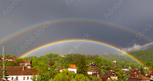 Obraz na płótnie A rainbow above a village. Landscape with a rainbow over countryside houses w salonie