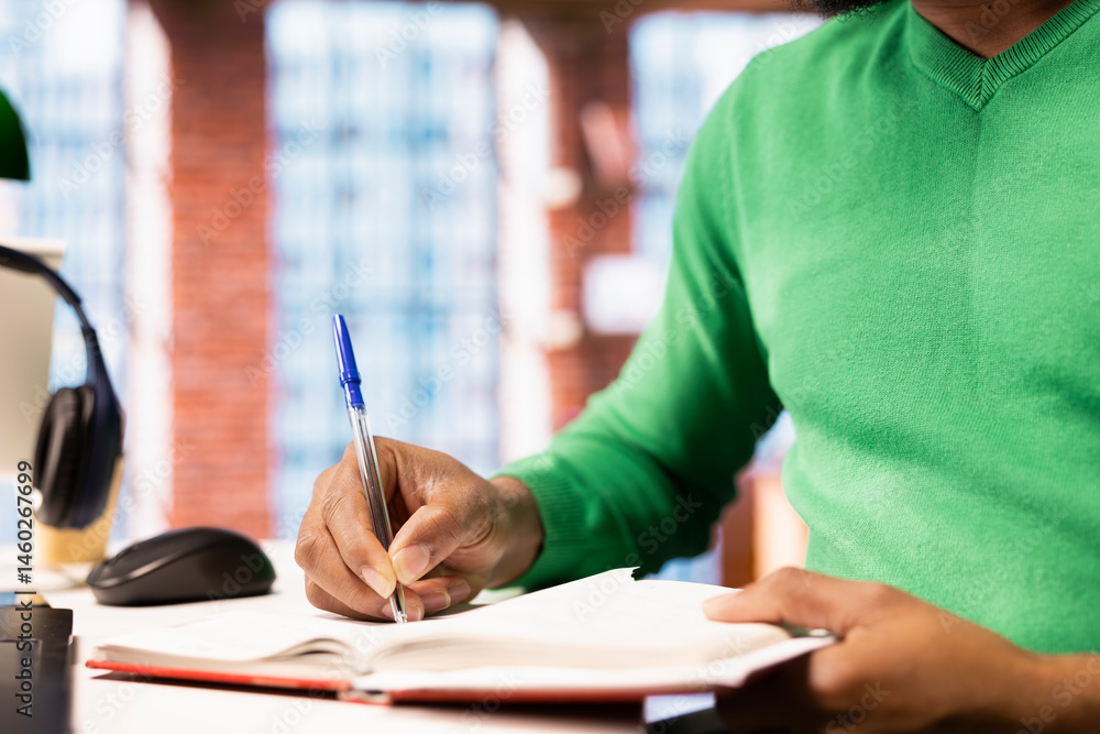 Person preparing for school exam, practicing on notepad at home office desk, close up. African american student doing homework, writing down info with pen, researching for college tests