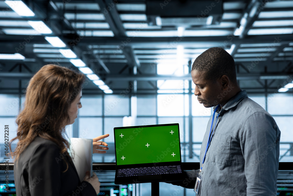 Employees in data center automating routine maintenance tasks with green screen laptop, executing diagnostic scripts. Server room workers using mockup notebook, adjusting power settings