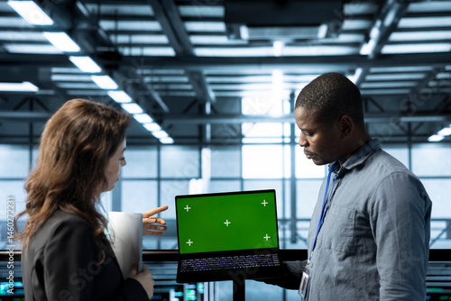 Obraz na płótnie Employees in data center automating routine maintenance tasks with green screen laptop, executing diagnostic scripts. Server room workers using mockup notebook, adjusting power settings w salonie
