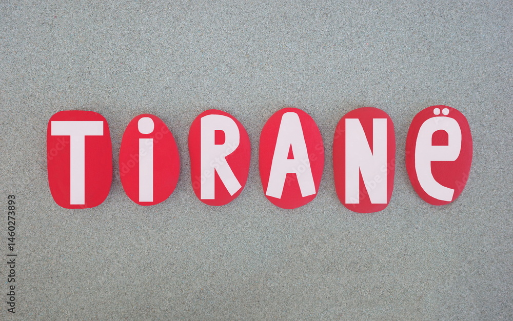 Fototapeta premium Tirane, albanian name of Tirana, capital city of Albania composed with red hand painted stone letters over green sand