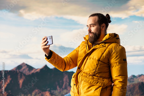 Hiker adventure seeker captures the breathtaking scenic view at the top of mountain, gazes at a distant mountain range and embraces beauty of the wilderness. Joy of discovering wonders.