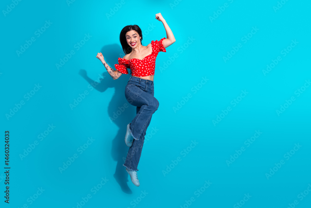 Energetic young woman in casual style enthusiastically leaping against a bright blue background, showing positivity Energetic young woman in casual style enthusiastically leaping against a bright blue background, showing positivity