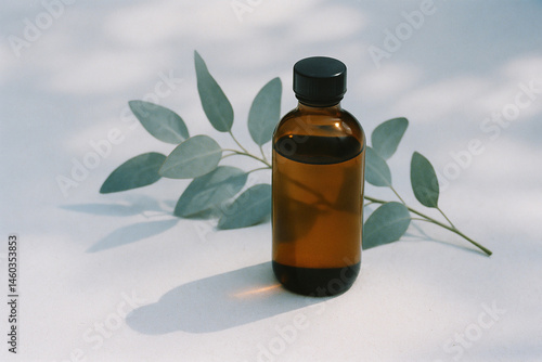 Obraz na płótnie Amber bottle of eucalyptus oil with soft blue foliage and shadows w salonie