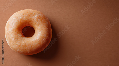 Glazed donut on brown background, showcasing simple food photography style with ample free space for text or branding