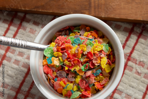 Fototapeta A top down view of a spoon scooping some popular rainbow flakes cereal