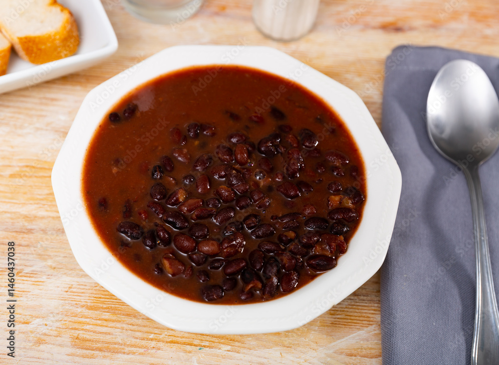 Mexican cooked black beans served in sauce on platter.. Mexican cooked black beans served in sauce on platter..