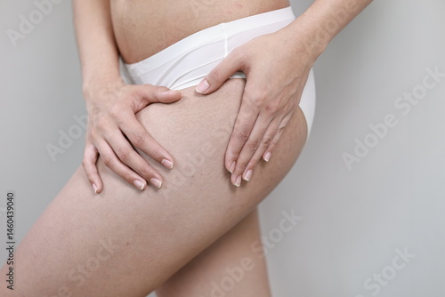 Wallpaper Mural A woman gently touches her abdomen, examining stretch marks and curves, symbolizing weight changes, self-care, and the journey through pregnancy, fitness, or surgery. Torontodigital.ca