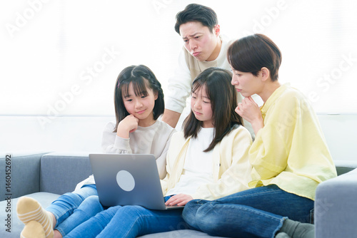 困った表情でパソコンを使う家族