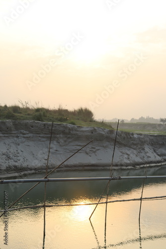 Obraz na płótnie River View with bamboo pole, sand texture, and sky, creating a scenic landscape w salonie