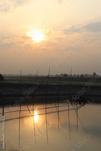 Obraz na płótnie Tranquil water reflection of bamboo bridge with golden sunlit sky at dusk w salonie