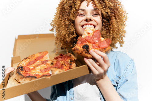 Obraz na płótnie Cheerful young woman enjoying delicious pizza, holding a slice and a pizza box, showcasing a vibrant lifestyle and love for comfort food w salonie