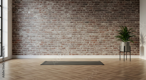 A dark gray yoga mat sits on the floor in minimalist yoga studio with a brick wall and a shiny white floor