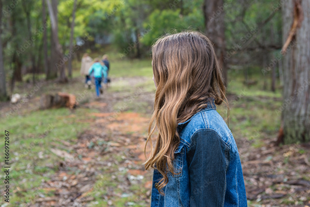 teen girl lagging behind a group of kids in a forest teen girl lagging behind a group of kids in a forest