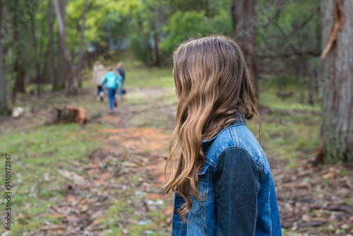teen girl lagging behind a group of kids in a forest