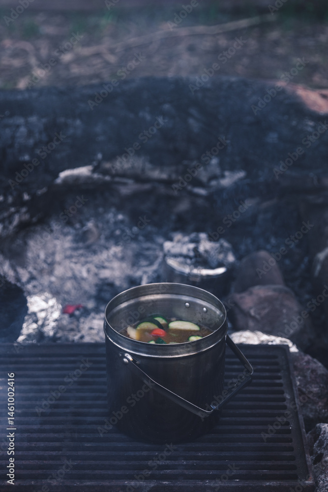 Pot of vegetable soup cooking on grill on campfire coals Pot of vegetable soup cooking on grill on campfire coals
