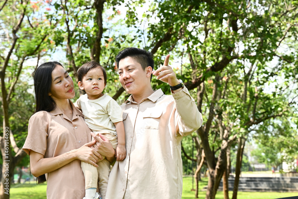 A family of four is walking in a park, the family appears to be happy and enjoying their time together.