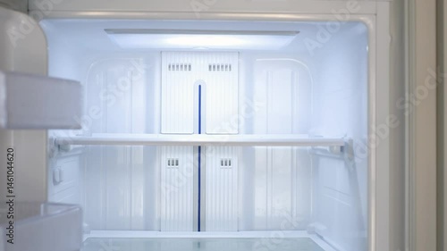 Modern white open refrigerator close-up with empty shelves, front view.