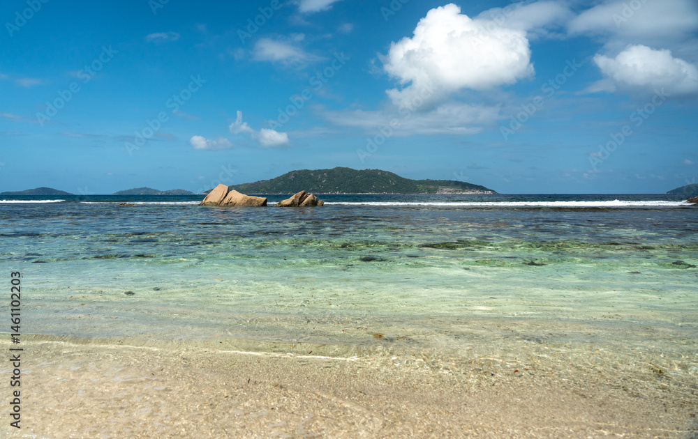 View of granite coastal rocks and ocean waves with distant islands on the horizon under cloudy