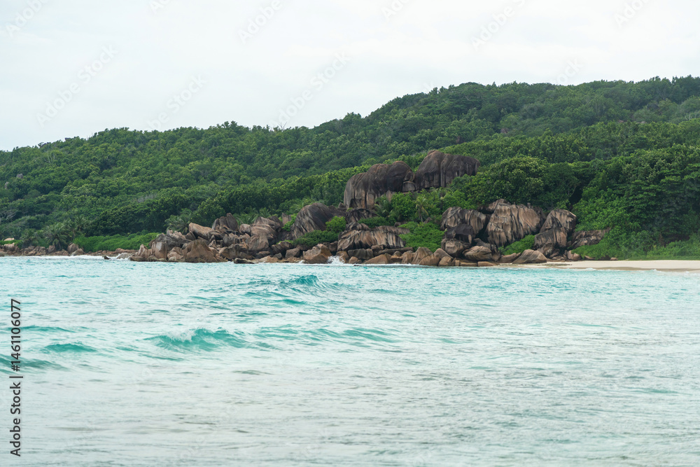 A typical Seychelles coast features granite boulders, dense tropical vegetation