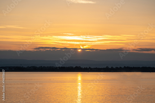Obraz na płótnie Sunset over the ocean, with the sun low on the horizon, contrast between sky and sea w salonie